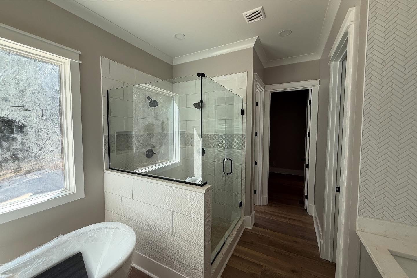 Primary bath with glass shower, freestanding tub, and textured tile